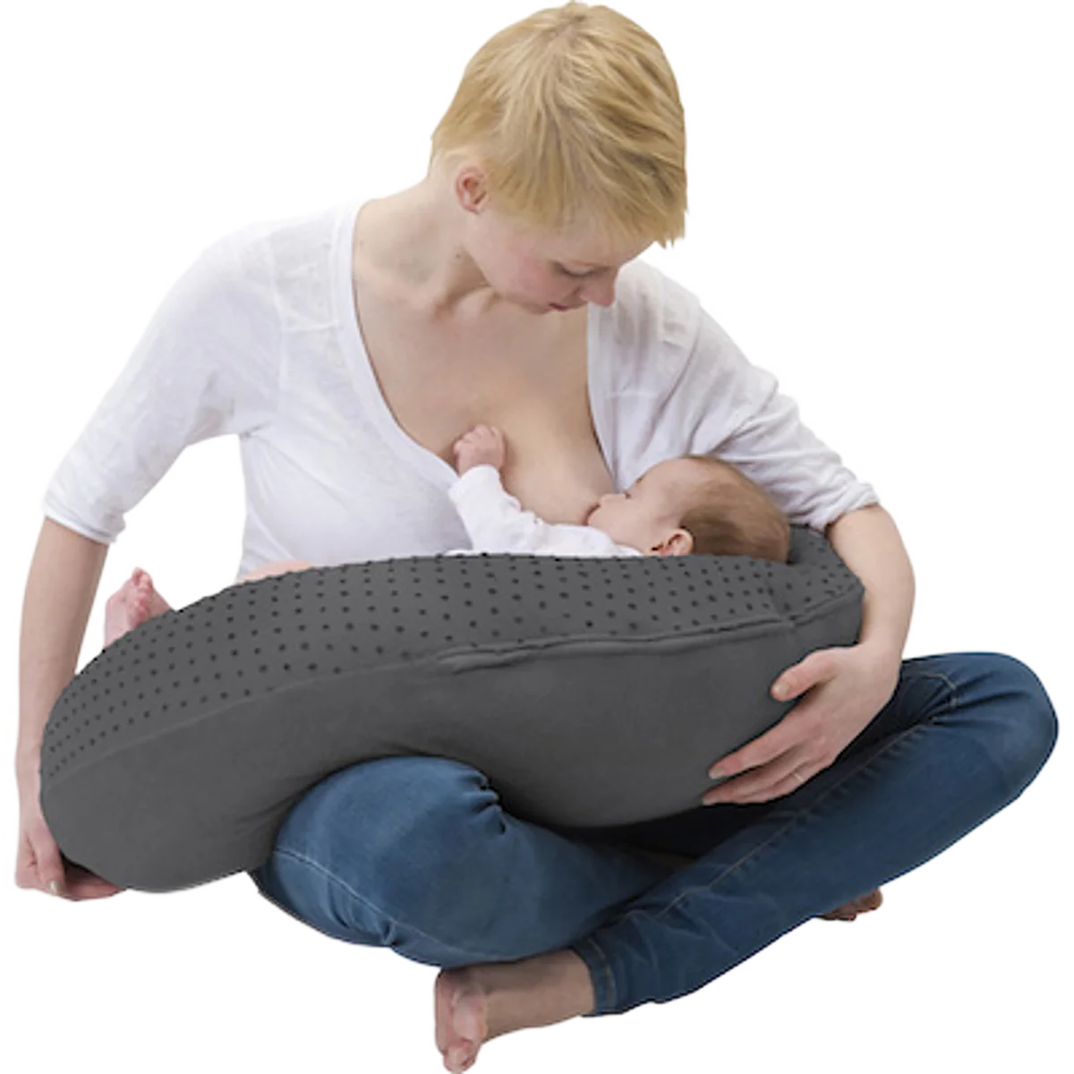 Une jeune femme assise en tailleur allaite son bébé, soutenu par un grand coussin d’allaitement gris à petits motifs de points.